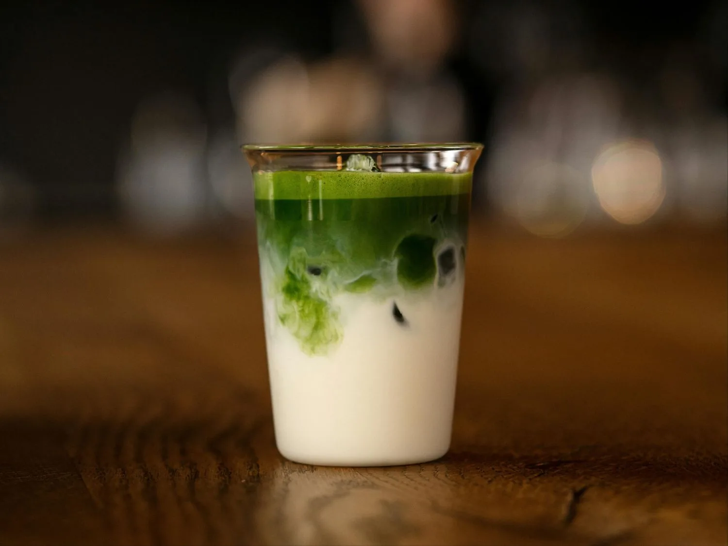 Ceremonial-grade matcha latte layered over creamy milk in a clear cup